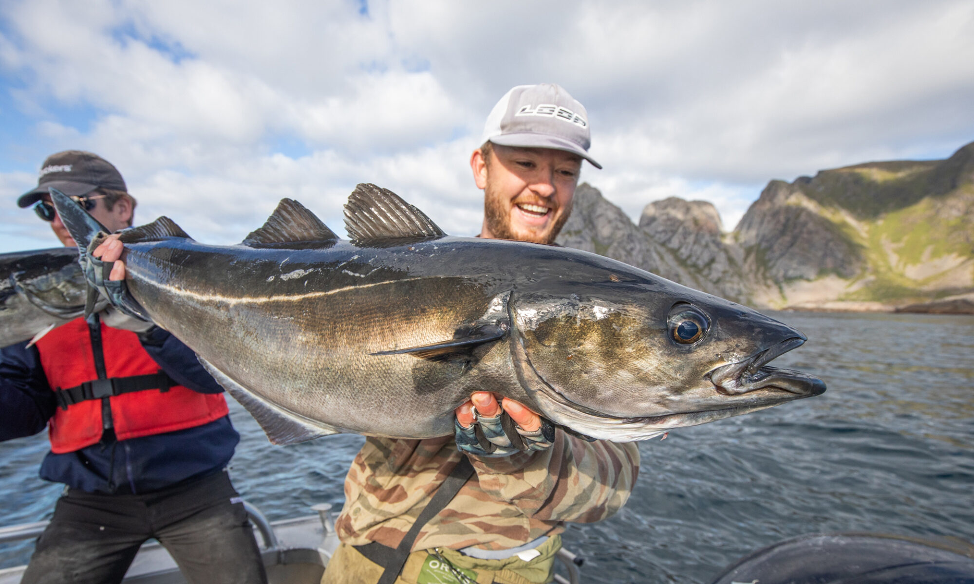 Un pescatore entusiasta con una cattura di halibut nelle acque cristalline delle Isole Lofoten, Norvegia